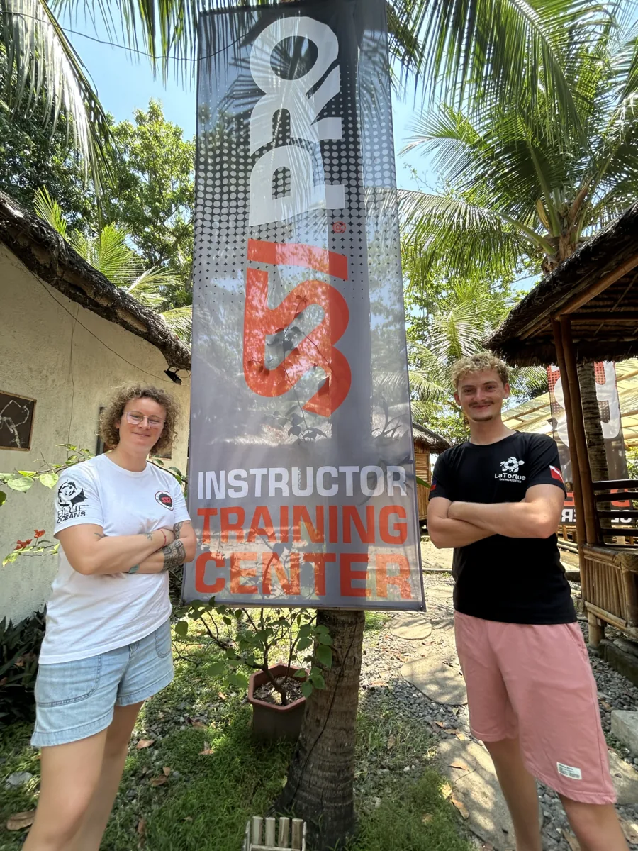 Antoine standing in front of the SSI Instructor Training Center banner at La Tortue